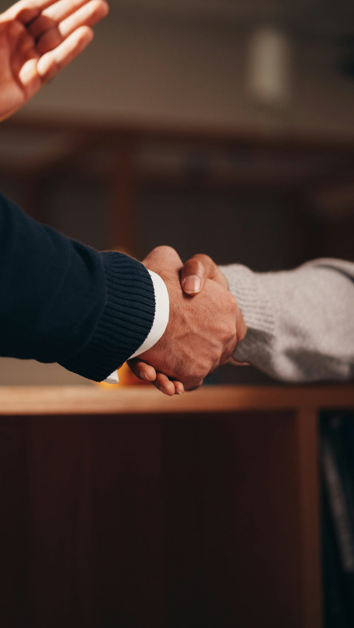 Aperto de mãos sobre a mesa ao final de uma reunião jurídica